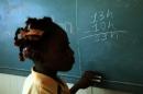 A student works on a math exercise on the blackboard after the visit of Former US President Bill Clinton to the school Union Des Apotres in Citie Soleil, Port au Prince, on 17 February 2014