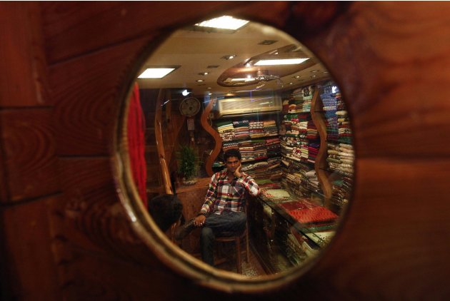 A shop attendant is pictured through a decorative window in his retail shop as he waits for customers in Mumbai