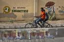 Two youths ride bicycles past a mural on a school wall and election posters supporting President Goodluck Jonathan, on a street in Kano, Nigeria Sunday, March 29, 2015. Voting in Nigeria's elections continued in certain areas on Sunday after technical problems prevented some people from casting their ballots on Saturday and despite extremist violence in the northeast and protests in the south. (AP Photo/Ben Curtis)