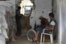 A Free Syrian Army fighter reads the Koran as his fellow fighter monitors the area through a hole in a wall in Deir al-Zor