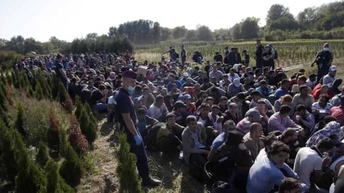 A group of migrants sits and waits to be escorted to a train after crossing a border from Croatia near the village of Zakany, Hungary, Wednesday, Sept. 23, 2015. Deeply divided European Union leaders have been called to an emergency summit to seek long-term responses to the continent&#39;s ballooning crisis of refugees and migrants, a historic challenge EU President Donald Tusk said the bloc has failed dismally to meet. (AP Photo/Petr David Josek)