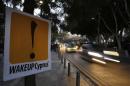 Vehicles speed past a sign placed by anti-Troika protesters outside the parliament in Nicosia