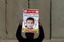 A Palestinian man carries a sign bearing a portrait of Palestinian journalist Mohammed al-Qiq, whose life is endangered after a 64-day-old hunger strike
