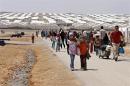 In this Wednesday, April 29, 2015 photo, Syrian refugees make their way at Azraq refugee camp, Jordan. A year after opening, this camp billed as a model for sheltering Syrian war refugees has emerged as a mixed blessing: Azraq offers safety and order, with its more than 10,000 prefab shelters arranged in tidy rows, but refugees say life is barely tolerable because of lack of electricity, jobs and freedom of movement. (AP Photo/Raad Adayleh)