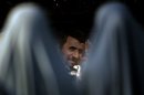 Iranian President Mahmoud Ahmadinejad is seen through two Shiite women