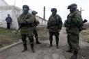 A boy looks at uniformed men near a Ukrainian military base in the village of Perevalnoye