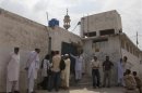 Members of the media and residents gather outside a mosque near the locked family house of Rimsha Masih on the outskirts of Islamabad