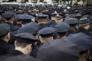 A lone police officer stands front as other colleagues turn their backs while Mayor Bill de Blasio speaks during the funeral of New York Police Department Officer Wenjian Liu at Aievoli Funeral Home, Sunday, Jan. 4, 2015, in the Brooklyn borough of New York. Liu and his partner, officer Rafael Ramos, were killed Dec. 20 as they sat in their patrol car on a Brooklyn street. The shooter, Ismaaiyl Brinsley, later killed himself. (AP Photo/John Minchillo)