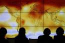 Participants looks at a screen projecting a world map with climate anomalies during the World Climate Change Conference 2015 (COP21) at Le Bourget