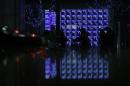 Pedestrians walk past an electronic board showing various stock prices outside a brokerage in Tokyo