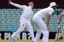 England Ashes Test cricketer Graeme Swann runs in to bowl past teammate Stuart Broad (R), during the tour match against a Cricket Australia Invitational XI in Sydney on November 16, 2013