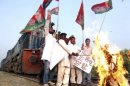 Activists burn an effigy of Indian Prime Minister Manmohan Singh after stopping a train during a strike