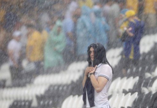 Man shelters himself during a heavy rain at Donbass Arena after the Group D Euro 2012 soccer match between Ukraine and France was suspended in Donetsk