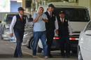 Former Ecuadorean deputy Galo "Tito" Lara Yepes flashes the V sign as he is escorted by the police upon his arrival to the Interpol headquarters in Panama City on June 9, 2014