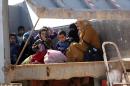 Iraqi women and children sit in the back of a truck at an army checkpoint at Ayn al-Tamer crossing at the entrance to Karbala province on January 6, 2014