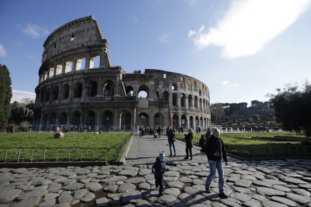 Tourists walk outside Rome's Colosseum, Friday, Jan. 18, 2013. A long-delayed restoration of the Colosseum's only intact internal passageway has yielded ancient traces of red, black and blue frescoes — as well as graffiti and drawings of phallic symbols — indicating that the arena where gladiators fought was far more colorful than previously thought. Officials unveiled the discoveries Friday and said the passageway would be open to the public starting this summer, after the €80,000 ($100,000) restoration is completed. The frescoes were hidden under decades of calcified rock and grime, and were revealed after the surfaces were cleaned. The traces confirmed that while the Colosseum today is a fairly monochrome gray travertine rock, red brick and bits of moss-covered marble, in its day its interior halls were a rich and expensive Technicolor. (AP Photo/Gregorio Borgia)