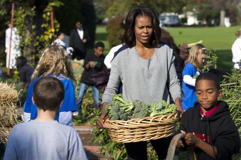 First Lady Michelle Obama harvests broccoli from the White House Kitchen Garden with school children on October 30, 2013