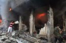This image taken from video filmed by an independent cameraman and made available on Tuesday, Sept. 4, 2012 shows a Syrian man throwing a bucket of water at a burning building in Myasar neighborhood, Aleppo, Syria. Government jets bombed the residential area of Myasar, reducing many of its buildings to rubble and causing a huge fire. (AP Photo/APTN)