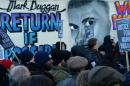 People stand outside a police station beside a banner depicting Mark Duggan in London, January 11, 2014, during a vigil following a jury verdict on January 8, 2014 ruling that Duggan was lawfully killed when he was shot dead by police in August 2011