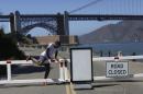 A runner climbs over a road gate leading to Fort Point National Historic Site, which has been closed due to the federal government shutdown, in San Francisco, California