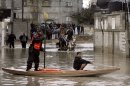 A Palestinian rescue worker helps a boy cross a flooded street in Rafah southern Gaza Strip, Wednesday, Jan. 9, 2013. In Gaza, civil defense spokesman Mohammed al-Haj Yousef said storms have cut electricity powering thousands of homes and rescuers were sent to evacuate dozens of people. (AP Photo/Eyad Baba)