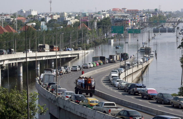 FILE - In this Oct. 24, 2011 file photo, cars are parked on an overfly on a flooded street in Bangkok, Thailand. Sea level rise projections show Bangkok could be at risk of inundation in 100 years unless preventive measures are taken. But when the capital and its outskirts were affected in 2011 by the worst flooding in half-a century, the immediate trigger was water run-off from northern provinces, where dams failed to contain unusually heavy rains. (AP Photo/Apichart Weerawong, File)