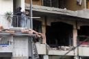 Residents stand on their balcony as they look at the site of an explosion that occurred yesterday in Beirut's southern suburbs