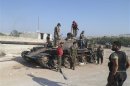 Members of the Free Syrian Army stand next to a captured Syrian Army tank in Bab Al Hawa