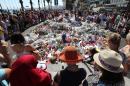 People gather near flowers placed at a makeshift memorial near the Promenade des Anglais in Nice on July 17, 2016, in tribute to the victims of the Bastille Day attack that left 84 dead
