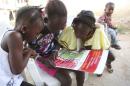 Girls look at a poster, distributed by UNICEF, bearing information on and illustrations of best practices that help prevent the spread of Ebola virus disease (EVD), in the city of Voinjama, in Lofa County in this handout photo