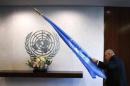 An attendant carries the United Nations flag into a meeting room before U.N. Secretary-General Ban Ki-moon meets Norway's Foreign Minister Borge Brende at U.N. headquarters in New York