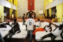 In this picture taken Sunday, June 15, 2014, migrants from Africa are temporarily sheltered in the Catholic church of St. Curato D'Ars in Palermo, Sicily, Italy. The Italian coast guard and navy have rescued more than 300 migrants whose boats ran into trouble in the Mediterranean Sea and recovered the bodies of 10 migrants whose dinghy had overturned, Sunday. Naval official Salvatore Scimone said 39 survivors on Saturday night had grabbed onto the dinghy until rescuers plucked them to safety aboard another boat. He said he feared that an undetermined number of others were missing in the sea north of Libya. In a separate rescue, three Italian ships took aboard 281 migrants who said they were Syrian and whose fishing boat ran into problems. (AP Photo/Alessandro Fucarini)