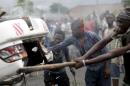Protesters destroy a car belonging to a policeman after they intercepted him at a barricade during demonstrations in Bujumbura