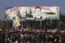 Pro-government supporters hold up the national Syrian flag and pictures of Syrian President Bashar Assad at a gathering at Saadallah al-Jabiri Square in Aleppo, Syria, Thursday, Jan. 19, 2017. Shells slammed into the northern Syrian city of Aleppo Thursday as thousands of government supporters gathered in the main square to celebrate last month's capture of the whole city by the army leading to a disperse by the gathering. (AP Photo/Hassan Ammar)