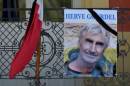 A portrait of mountain guide Frenchman Herve Gourdel hangs near a French flag outside the town hall in Saint-Martin-Vesubie