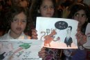 Syrian children hold up signs during a night demonstration at Sarmada on the outskirts of Idlib