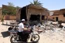 A man from the Berber community rides a motorcycle a wrecked house on July 9, 2015 following clashes between Berbers and Arabs in the Algerian town of Guerara