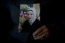 In this photo taken Saturday, Feb. 1, 2014, Palestinian Khadra al-Akhras poses with a photo of her late daughter Ayat al-Akhras who blew herself up in a suicide bombing outside a Jerusalem supermarket in 2002, at the family house in the West Bank city of Bethlehem. More than a decade later, after appeals from human rights groups, Israel is handing over some 30 bodies of Palestinian assailants, including that of Ayat. (AP Photo/Nasser Nasser)