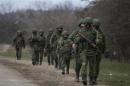 Armed men, believed to be a Russian servicemen, walk as they change shifts near a military base in Perevalnoye, near the Crimean city of Simferopol