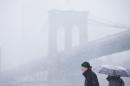 People wait on a ferry boat in view of the Brooklyn Bridge, during a winter snowstorm Monday, Feb. 3, 2014, in the Brooklyn borough of New York. After several days of milder weather, snow has returned to the Northeast. (AP Photo/Matt Rourke)