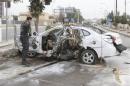An Iraqi security forces personnel inspects a car after a bomb in Kirkuk