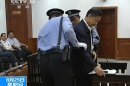 Ousted Chinese political star Bo Xilai (R) is helped to sit in his dock in the courtroom in Jinan, August 25, 2013