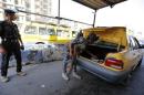 A member of Iraqi security forces searches the trunk of a vehicle at a checkpoint, as security increases in Baghdad