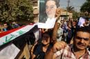 Iraqi mourners hold up a picture of a slain journalist, as they carry a symbolic coffin draped in an Iraqi flag in certral Baghdad on September 9, 2011