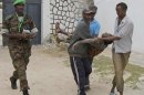 Somali police men carry an injured Somali soldier in Mogadishu Wednesday Aug.1, 2012 . The soldier was injured after two suicide bombers who were trying to blow up the constituent assembly venue were shot dead by security forces police said.(AP Photo/Farah Abdi Warsameh)