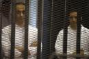 Gamal and Alaa Mubarak, sons of Hosni Mubarak, stand behind bars during their trial at the police academy, on the outskirts of Cairo