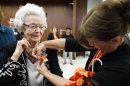 In this Sept. 23, 2013, Audrey Crabtree, 99, left, smiles as Sarah Dierks pins a 1972 East High homecoming pin onto her jacket during an during an education board meeting in Waterloo, Iowa, where she received an honorary diploma. Crabtree dropped out of a Waterloo high school in 1932 due to an injury and to care for her grandmother. She went on to run her own business for nearly three decades. (AP Photo/Waterloo Courier, Tiffany Rushing)
