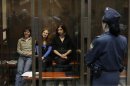 Members of the female punk band "Pussy Riot" sit in a glass-walled cage before a court hearing in Moscow