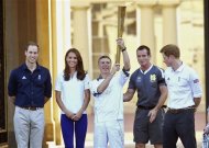 Britain's Prince William, along with Catherine, Duchess of Cambridge and Prince Harry watch as Olympic torch bearer John Hulse (C) carries the flame during a visit to Buckingham Palace in London July 26, 2012. REUTERS/Ian West/Pool