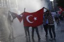 Protesters hold a Turkish flag as riot police use a water cannon to disperse them at Taksim square in central Istanbul
